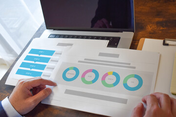 ノートパソコンと資料を確認する男性