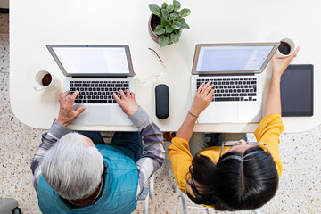 Overhead shot of grandfather working with granddaughter at table