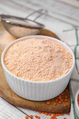 Bowl of lentil flour and seeds on white wooden table