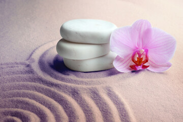 Obraz na płótnie Canvas Stack of white stones and beautiful flower on sand with pattern. Zen, meditation, harmony
