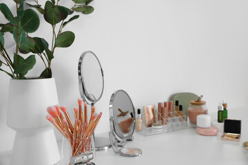 Holder with different makeup brushes on light table