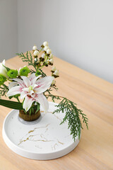 Beautiful ikebana on wooden table near light wall