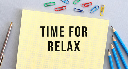 TIME FOR RELAX text in notebook on gray background next to pencils, pen and paper clips.
