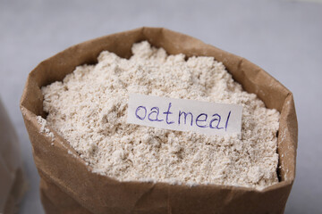 Sack with oatmeal flour on light table, closeup