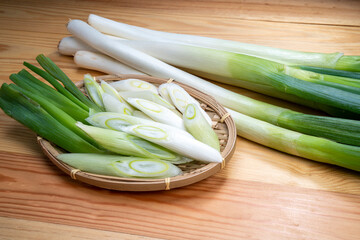 Fresh Japanese Bunching Onion on bamboo basket, Green Japanese spring onions on wooden background.