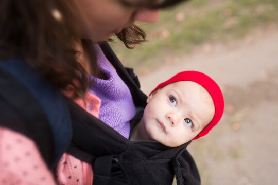 Baby with red in baby carrier looking at mother