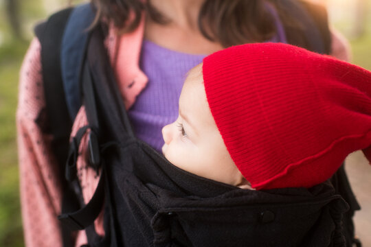 Baby with red in baby carrier looking away