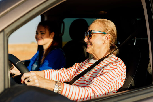 Mature woman driving a SUV car with teen in a road trip