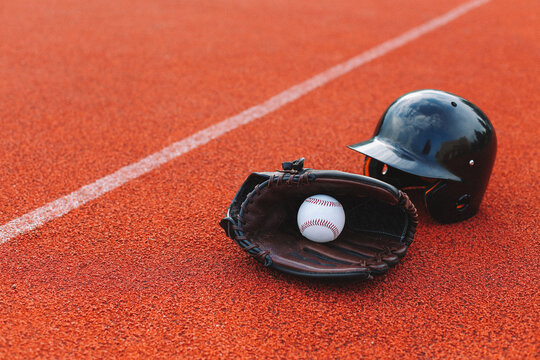 Baseball glove, baseball and helmet on the field. 