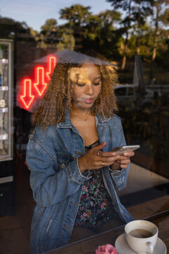 Happy woman using cellphone at coffee shop