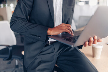 Close up of african businessman hands working on laptop while sitting in office
