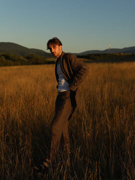 Young man wearing minimal style clothes and posing in golden fields 