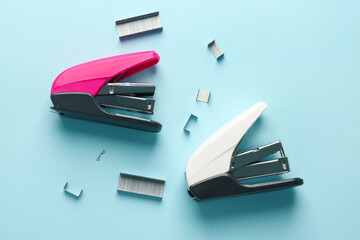 Office staplers and staples on color background