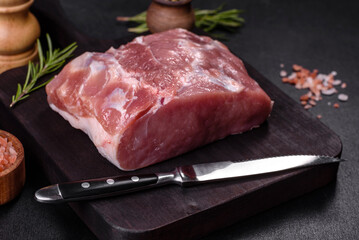 Fresh piece of raw pork with spices, salt and herbs on a wooden cutting board
