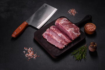 Fresh piece of raw pork with spices, salt and herbs on a wooden cutting board