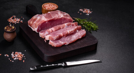 Fresh piece of raw pork with spices, salt and herbs on a wooden cutting board