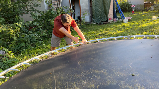 Man is busy with unhooking strings of trampoline