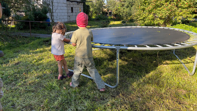 Preschool siblings standing at their backyard and holding