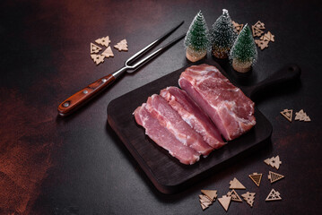 Fresh piece of raw pork with spices, salt and herbs on a wooden cutting board