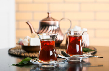 Saucer with glass of Turkish tea and leaf on table in room, closeup
