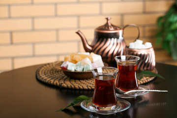Saucer with glass of Turkish tea and leaf on table in room, closeup