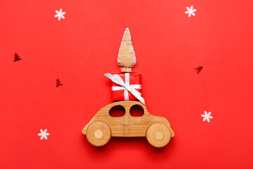 Toy car with Christmas tree and gift on red background