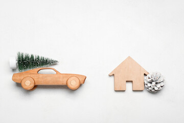 Toy car with Christmas tree, fir cone and house figure on white background
