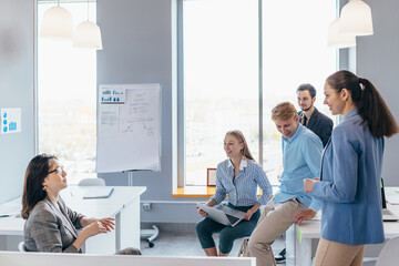 Business woman making a presentation to her colleagues during meeting or in-house training, explaining business plans to her employees