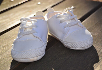 White little sneakers for baby on the wooden floor