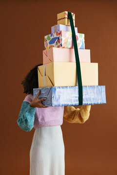 Anonymous woman with stack of colorful Christmas gifts