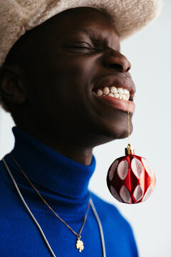 Playful black guy with bauble in teeth