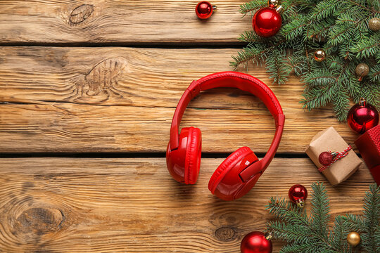 Composition with modern headphones, Christmas gift, balls and fir branches on wooden background