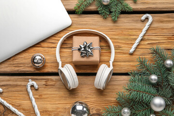 Obraz na płótnie Canvas Composition with modern headphones, laptop, Christmas decorations and fir branches on wooden background