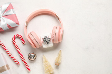 Composition with modern headphones, Christmas gifts, decorations and candy canes on light background