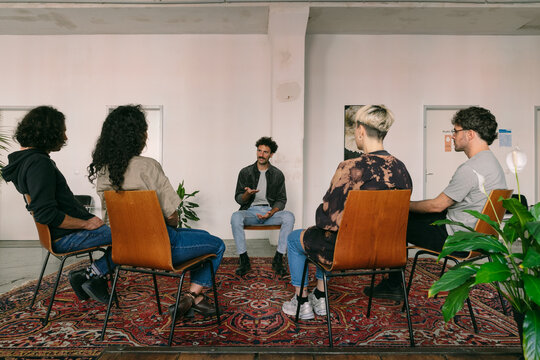 Male Hispanic Therapist Talking to Group of Four Clients