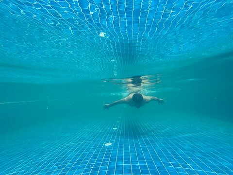 Middle aged Indian man swimming in a swimming pool 