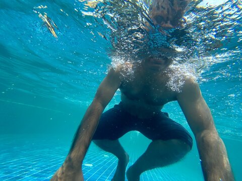 Middle aged Indian man swimming in a swimming pool 