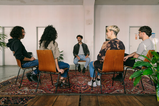 Smiling Male Hispanic Therapist Leading Group Session With Four 
