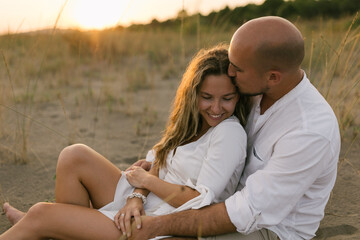 Close up portrait of young couple in love sitting at the beach