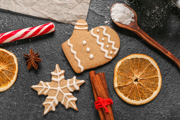 Tasty Christmas cookies, orange slices and spices on dark background