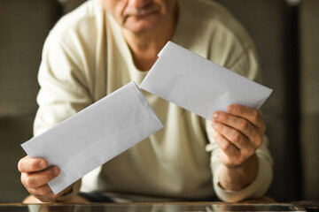 Senior man received a letter with utility bill and debts in period of energy crisis. High heating prices concept.