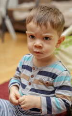 Fototapeta premium Portrait of a little angry boy sitting in an armchair