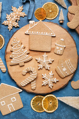 Wooden board with tasty Christmas cookies on color background