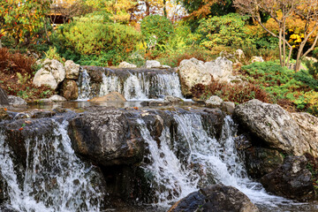 View of autumn park with beautiful waterfall