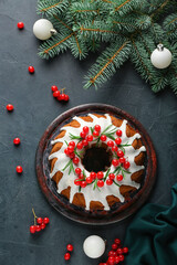 Traditional Christmas cake with cranberry, fir branches and balls on dark background