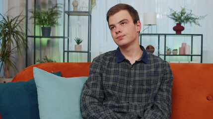 Portrait of sad teen man sitting at home looks pensive thinks over life concerns or unrequited...