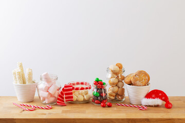 christmas candies and cookies  in jars on wooden shelf on white background