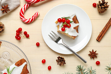 Plate with piece of tasty Christmas cake on light wooden background