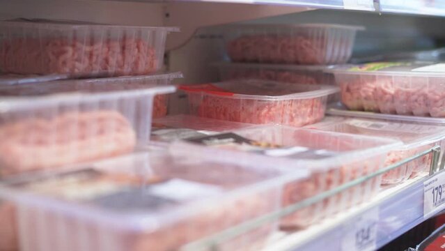 picks out minced meat in the supermarket's refrigerated compartment. closeup 