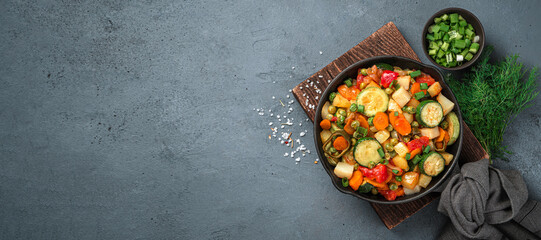 Vegetable stew with fresh herbs on a dark background. Healthy food. Top view, copy space.
